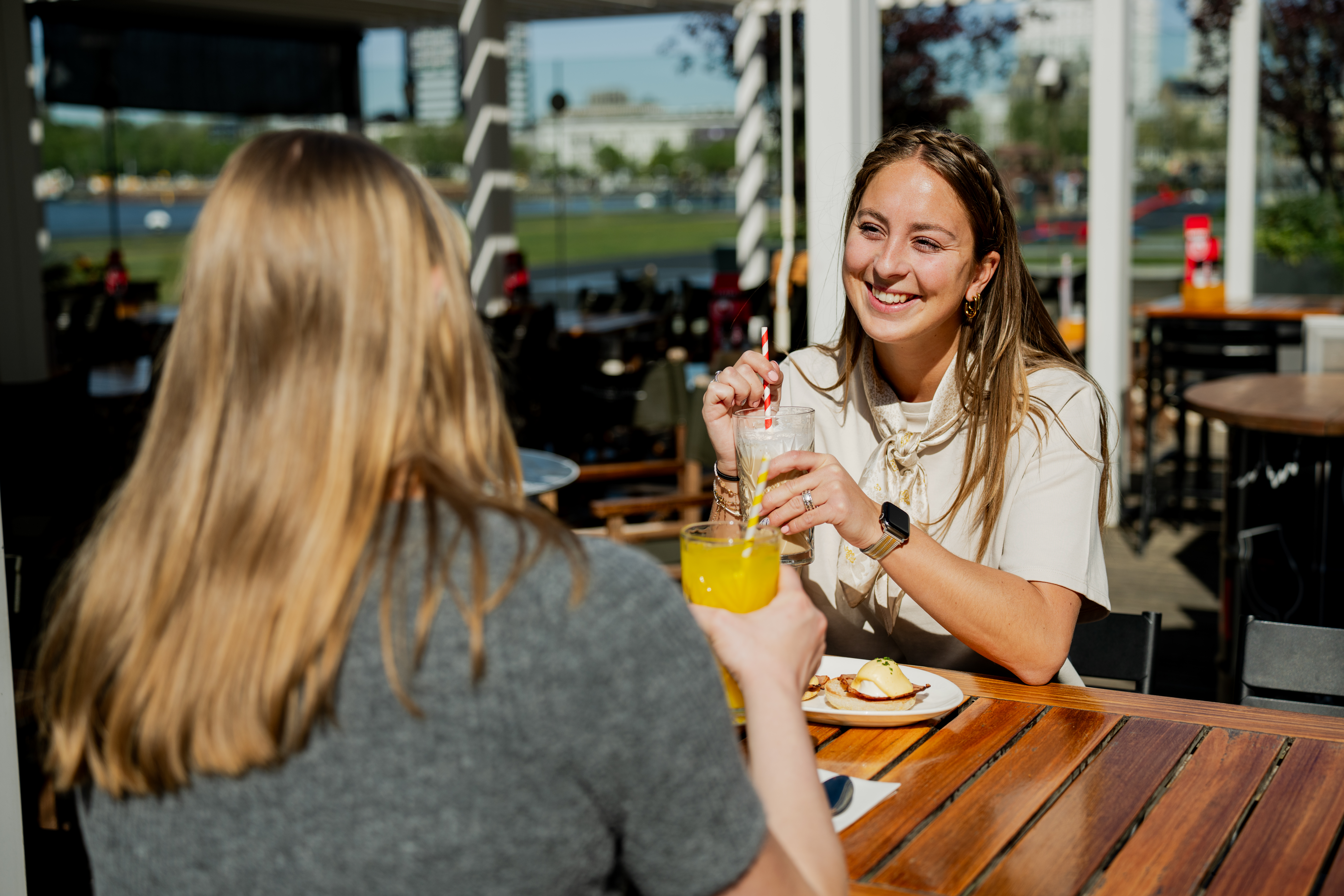 2 vrouwen lachen naar elkaar en zijn aan het genieten van ontbijt en drankjes